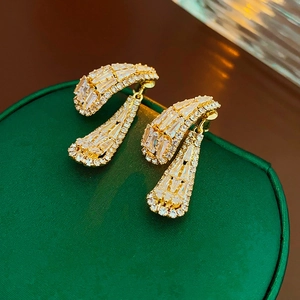 Gros plan de boucles d'oreilles pendantes dorées avec zircons sur boîte en soie verte