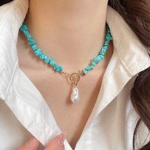 Close-up of bohemian turquoise beaded necklace with baroque pearl and gold T-bar clasp