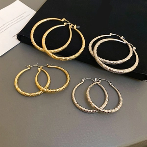 Detailed view of hammered texture hoop earrings in gold and silver finishes