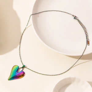 Macro shot of asymmetric heart pendant featuring rainbow plating and S.STEEL engraving