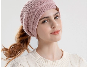 Detail of pink knitted beanie with a practical ponytail hole for long hair on a model