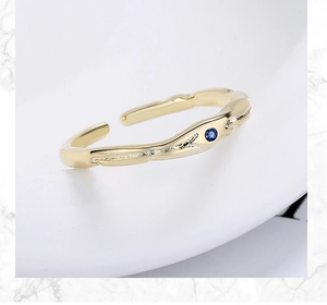 Détail d'une bague dorée ajustable avec zircon bleu et texture de branche unique