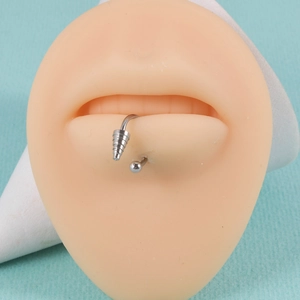 Close-up of silver punk horseshoe lip ring with cone and ball ends on a model