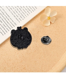 Detail view of the enamel pin back texture and butterfly clasp on a warm surface