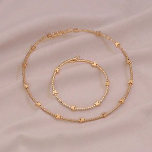 Detailed top view of gold butterfly necklace and bracelet set on soft fabric background
