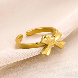 Macro shot of gold bow knot open ring on silk fabric showing polished mirror finish