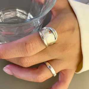 Close-up of minimalist polished silver rings set paired with a white shirt and glass