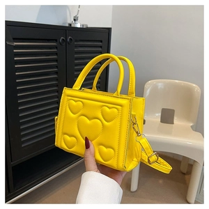 Détail d'un sac à main jaune en cuir PU avec motifs de cœurs embossés et boucle dorée