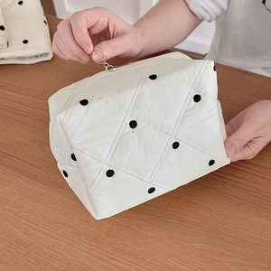 Détail de la fermeture éclair argentée sur la trousse à maquillage à pois matelassée