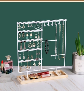 Close-up of metal jewelry stand with necklace hooks and wooden base on a table