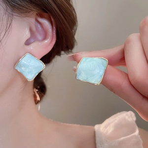 Detail of light blue resin tulip petal earrings with golden metal borders on model