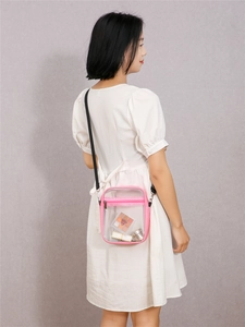 Detail view of pink trim and zipper on a transparent PVC crossbody jelly bag with strap