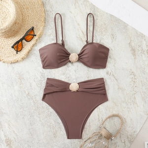 Detailed flat lay of brown bikini with golden shell buckles and sun hat on marble