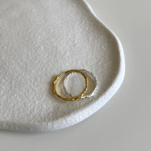Detail of adjustable gold and silver wave rings with handcrafted hammered texture on a tray