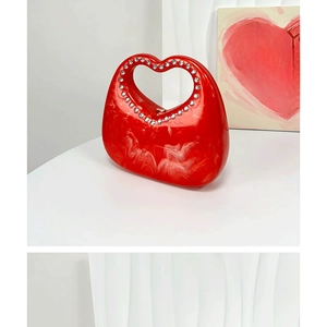 Close-up of red marble acrylic handbag featuring a sparkling rhinestone heart handle