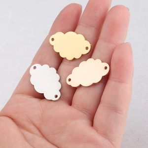 Detailed view of gold and silver cloud-shaped metal pendants held in hand for scale