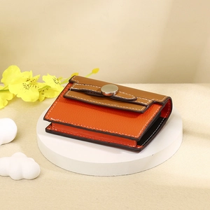 Detail of the orange and brown leather card holder with white stitching and metal snap button