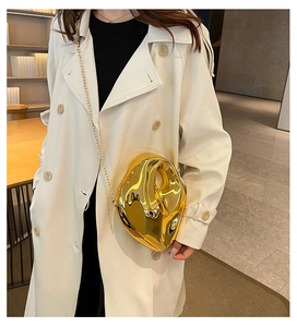 Detailed view of irregular gold acrylic clutch bag with metallic luster and chain strap