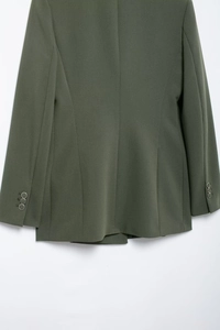 Détail de la manche d'un blazer vert olive avec trois boutons métalliques sur le tissu