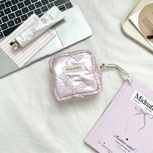 Detailed flat lay of a pink quilted bow cosmetic bag with chic lifestyle accessories