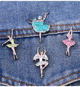 Detalle de cuatro pines de esmalte de bailarina sobre fondo de tela vaquera azul