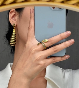 Detailed view of luxury 18k gold plated snake ring with green stone eyes and black enamel