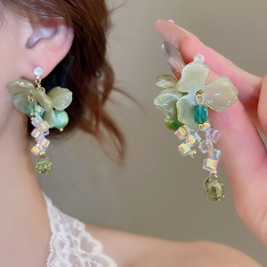 Close-up of elegant green flower earrings with long glass bead tassels and crystal drops