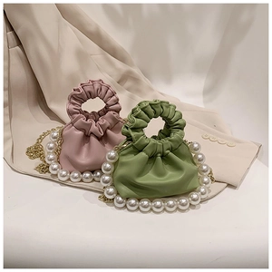 Close-up of pink and green mini leather handbags with pearl chains and ruffled top handles