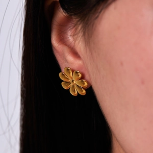 Minimalist flower stud earrings in 18K gold plated stainless steel on a model's ear