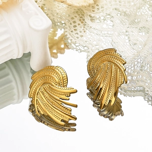 Détail de boucles d'oreilles dorées en forme d'éventail sur miroir avec dentelle