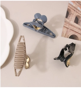 Close-up of hair claw clips in blue, khaki, and black with heart-shaped metal details