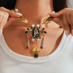 Close-up of vintage gold necklace with pearls and colorful gems on model