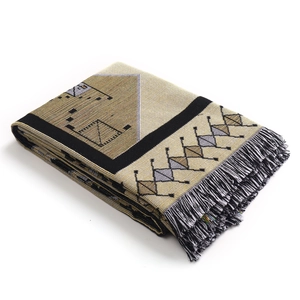 Detailed view of woven geometric patterns and black and white fringe on the throw blanket