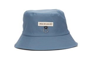 Detail of navy cotton bucket hat featuring an embroidered label and metal ring accent