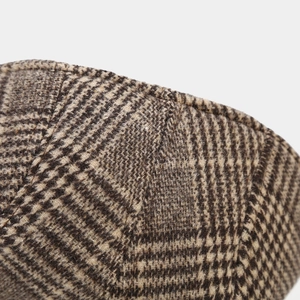 Close-up of wool houndstooth pattern fabric with detailed stitching on winter flat cap