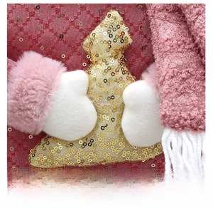 Detail eines rosa Weihnachtsstrumpfes mit goldenem Paillettenbaum und Stricktextur
