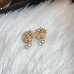 Macro shot of gold plated cluster earrings with micro pearls on white faux fur background