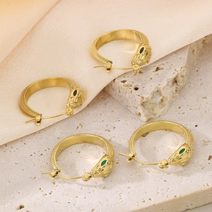 Detail of gold snake earrings with black and green enamel eyes on silk texture