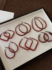 Set of six pairs of dark red geometric earrings including hoops and squares on a display tray