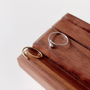 Close-up of minimalist gold and silver teardrop open rings on a wooden display stand