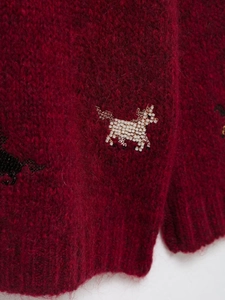 Macro shot of detailed white bead-embroidered horse on burgundy mohair knit sweater
