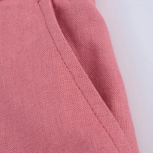 Detailed close-up of stitching on pink linen blend fabric shorts with pocket texture