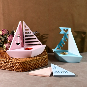 Dettaglio di portacandele a forma di barca a vela in blu e rosa con motivi ad ancora