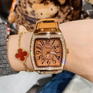 Detail of Dimini rose gold tonneau watch with orange leather strap and crystal bezel