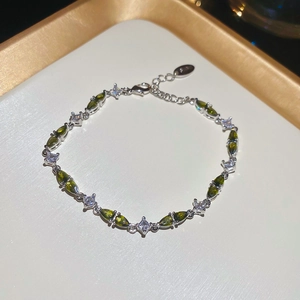 Detailed macro view of the silver bracelet with green and white zircon stones on a tray