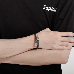 Detail of a black braided steel cable cuff bracelet with silver metal ends on a wrist