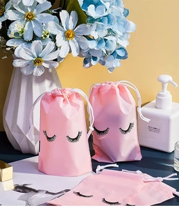 Detailed view of pink drawstring makeup pouches with eyelash print in a vanity setting
