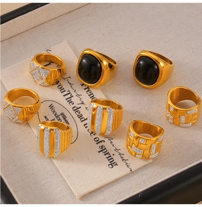 Detail of 8 gold-plated rings with black onyx and crystals on elegant fabric background