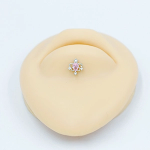 Vue détaillée d'un piercing de nombril avec zircon rose en goutte sur modèle en silicone