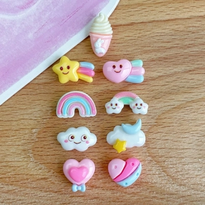 Flat lay of mini colorful resin charms featuring clouds rainbows and hearts on wood